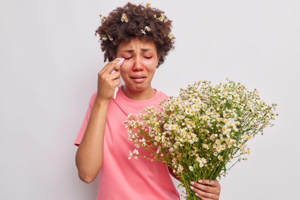 Woman feels unwell due to red eyes with kerchief suffers from seasonal allergy
